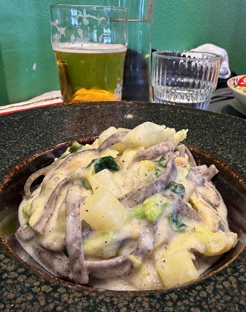 Pizzoccheri della Valtellina dish with buckwheat pasta, cabbage, potatoes, and melted cheese.