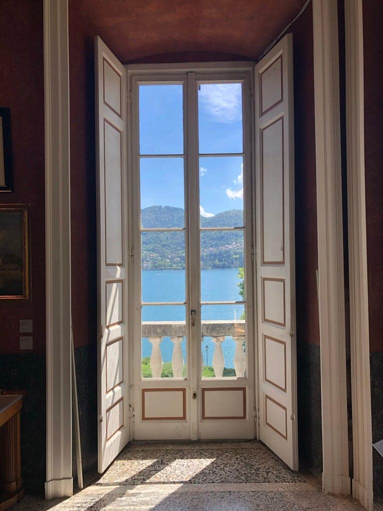 View of Lake Como from inside the Villa Carlotta museum showing the 19th-century architecture and window frames.
