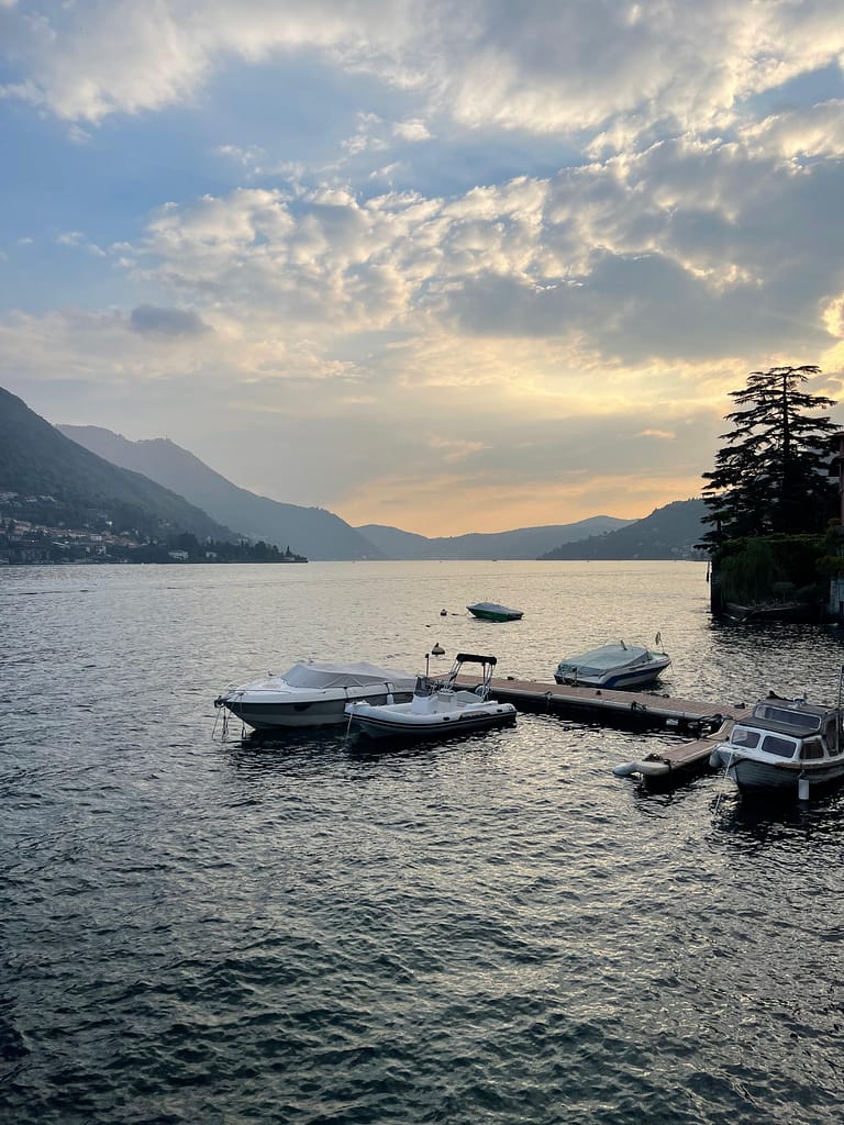 Scenic sunset on Lake Como with small boats in the foreground during a evening boat tour.