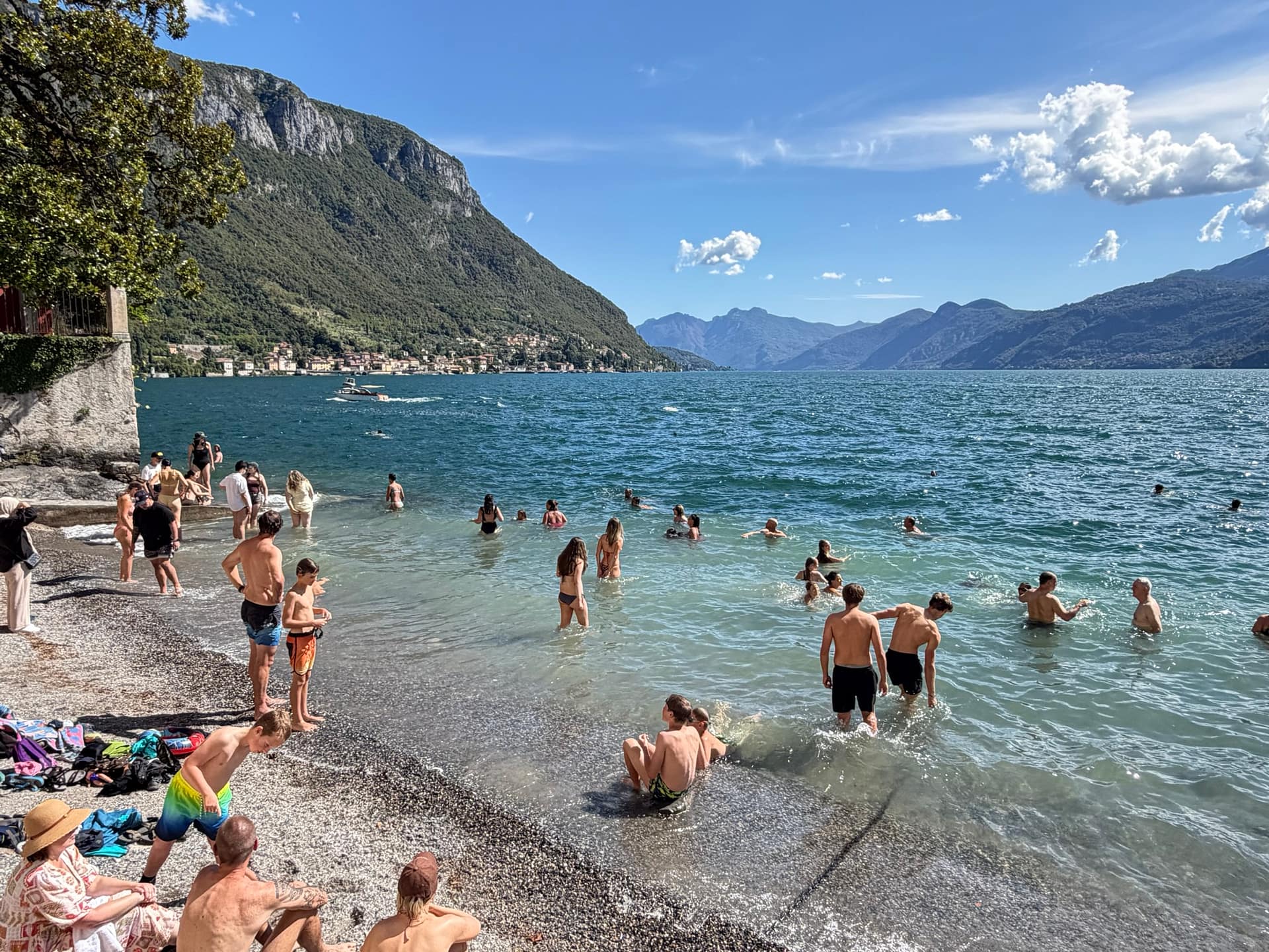 People swimming and relaxing at a small beach in Varenna
